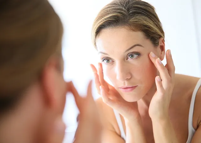 mujer se toca las ojeras en espejo